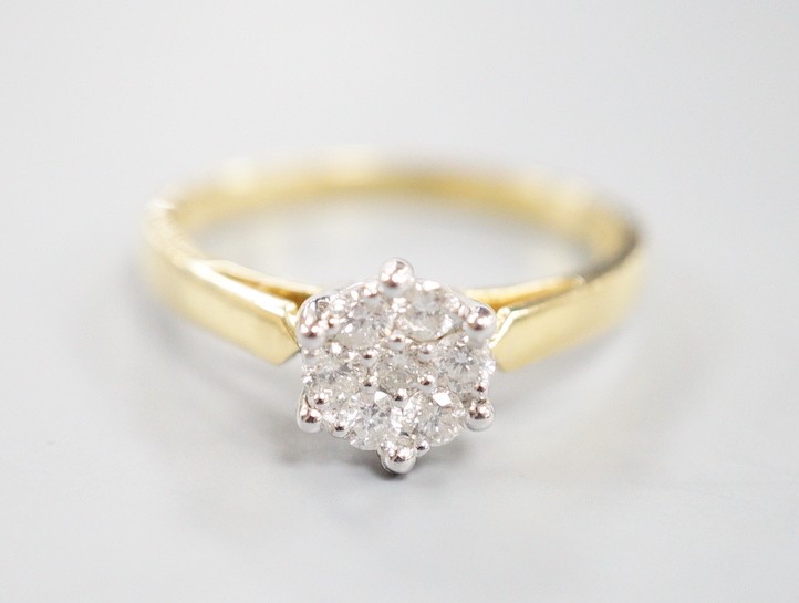 A modern 18ct gold and seven stone diamond set circular cluster ring, size P, gross weight 3.7 grams